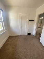 Unfurnished bedroom with dark colored carpet and baseboards