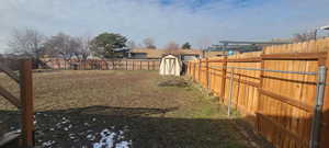Fenced backyard featuring a shed