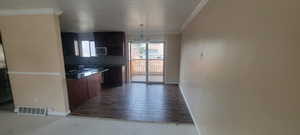 Kitchen featuring wood finished floors, a chandelier, dark stone countertops, decorative backsplash, and crown molding