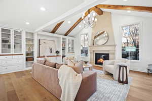 Living room featuring a fireplace, light wood-type flooring, and a chandelier