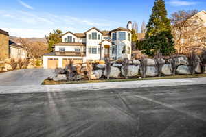 View of front of home with driveway, a standing seam roof, a mountain view, and a chimney