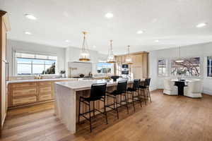Kitchen with light wood finish cabinetry, a kitchen breakfast bar, light stone countertops, light wood-type flooring, and a textured ceiling