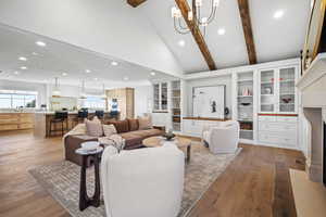 Living area featuring suspended lighting, vaulted ceiling, and light wood-style flooring