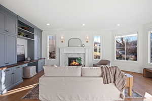 Living room featuring a premium fireplace, plenty of natural light, dark wood-style flooring, and recessed lighting