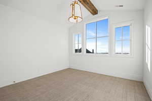 Spare room with beam ceiling and light carpet