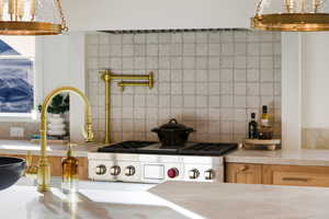 Kitchen featuring decorative backsplash, light countertops, and gas range