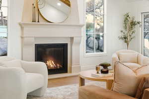 Sitting room with a glass covered fireplace and wood finished floors