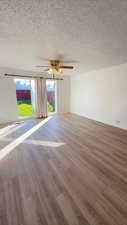 Unfurnished room with wood finished floors, a textured ceiling, and a ceiling fan