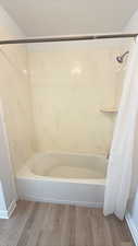 Bathroom featuring shower / tub combo and light wood-style floors