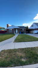 Single story home featuring brick siding, a chimney, concrete driveway, and an attached carport