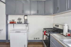 Kitchen featuring stainless steel gas range, gray cabinets, and dark wood-type flooring