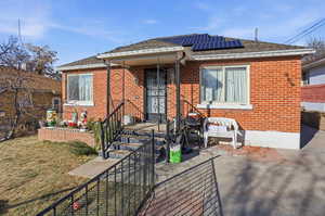 Back of house featuring solar panels, brick siding, and a shingled roof