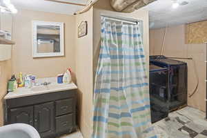 Bathroom with curtained shower, vanity, a textured wall, a textured ceiling, and independent washer and dryer