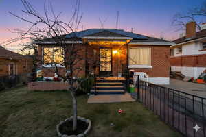 View of front of property featuring roof mounted solar panels, brick siding, and a patio area