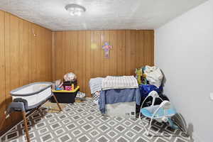 Bedroom with wooden walls, a textured ceiling, and tile patterned floors