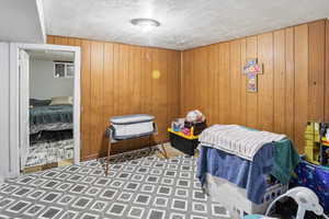 Bedroom featuring a textured ceiling and wood walls