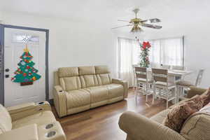 Living room featuring wood finished floors, ceiling fan, and a textured ceiling