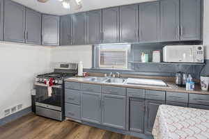 Kitchen featuring gray cabinetry, gas stove, white microwave, and ceiling fan