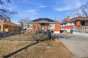 View of front of property with brick siding, solar panels, and concrete driveway