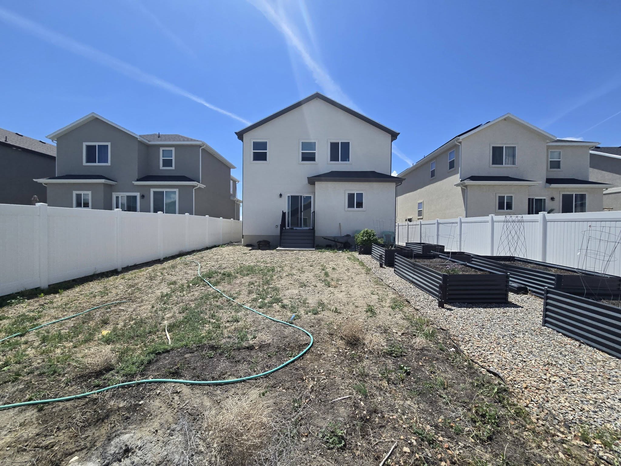 Back of house featuring a vegetable garden, a fenced backyard, and stucco siding