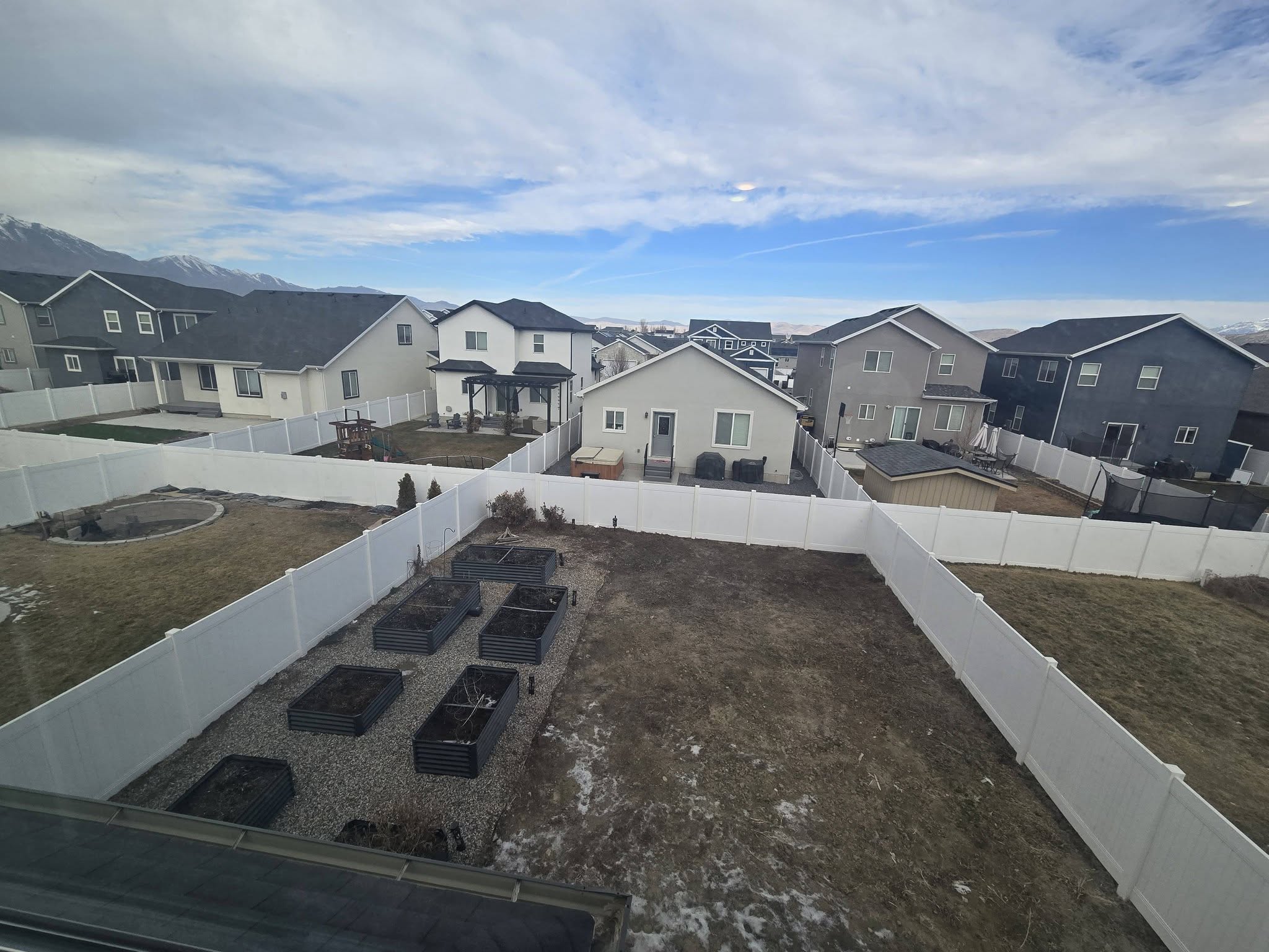 Fenced backyard with a residential view and a vegetable garden
