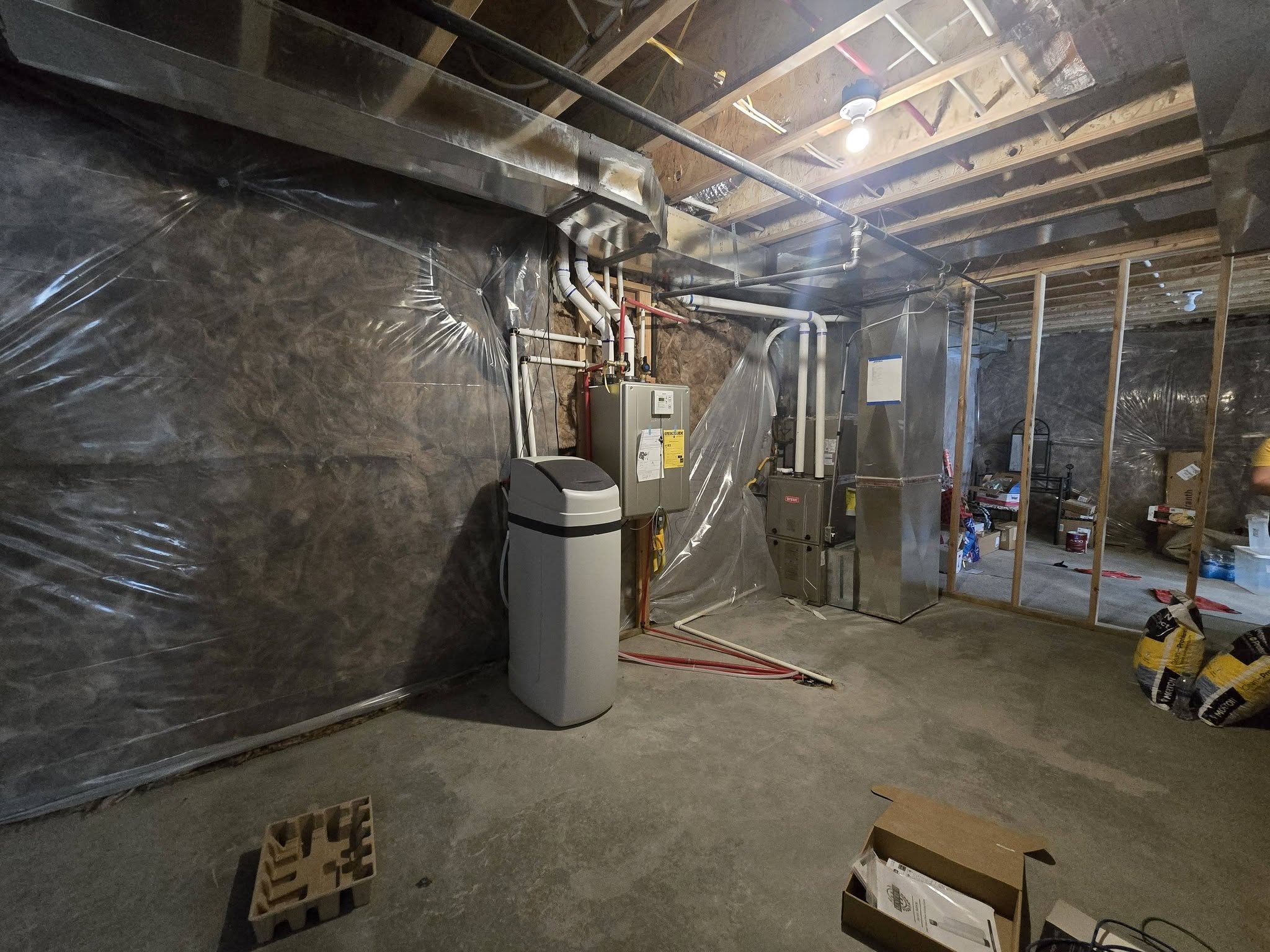 Unfinished below grade area with heating unit, a water softener, and water heater