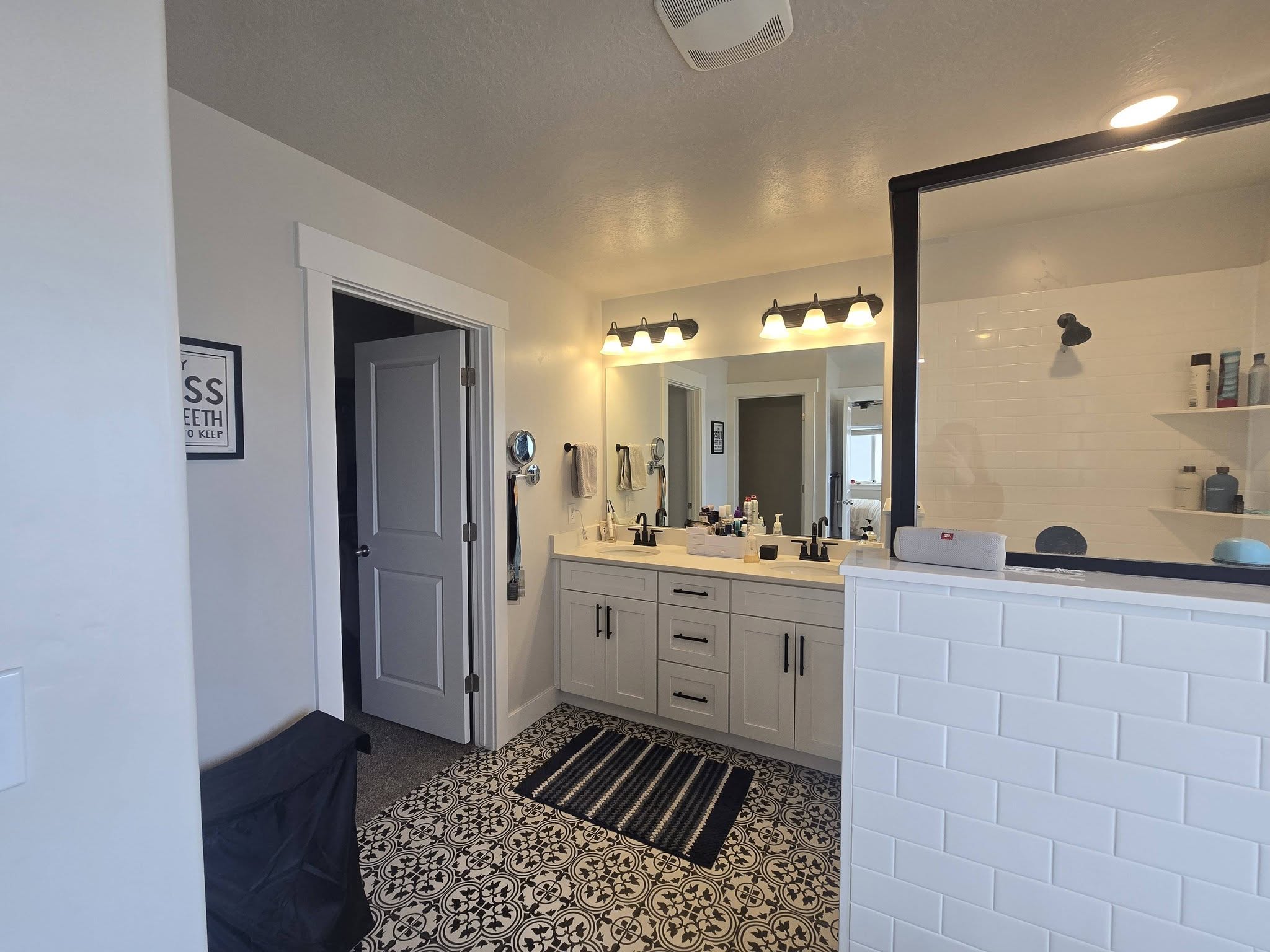 Full bath featuring tiled shower and double vanity
