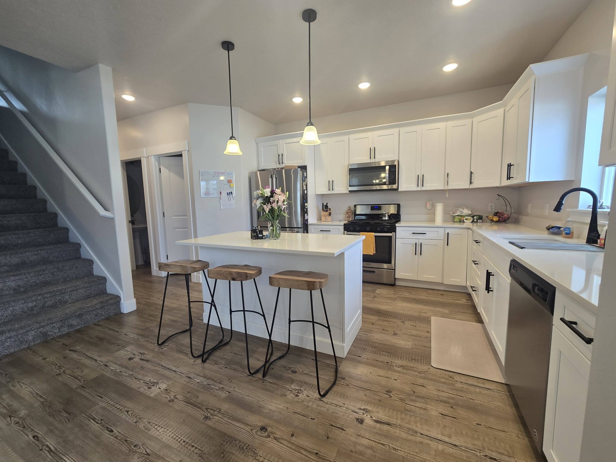 Kitchen with white cabinets, stainless steel appliances, a kitchen island, and decorative light fixtures
