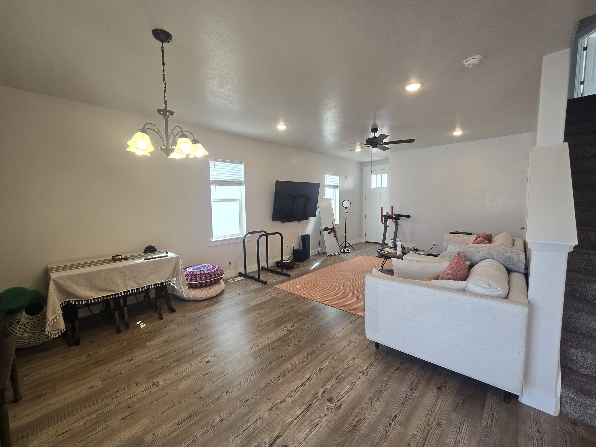 Living room with wood finished floors, hanging lights, a ceiling fan, and plenty of natural light