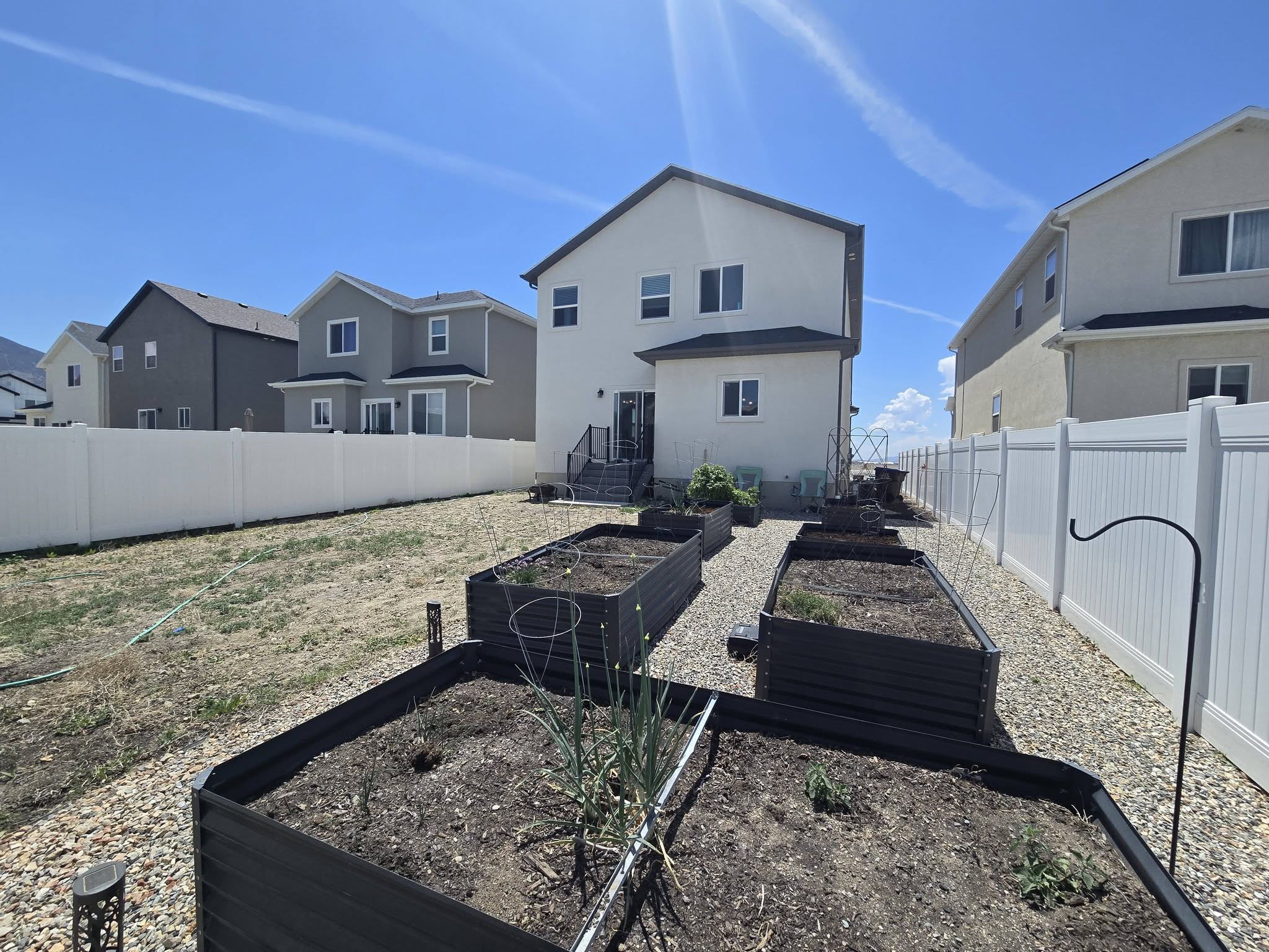 Back of property with a fenced backyard, a residential view, a vegetable garden, and stucco siding