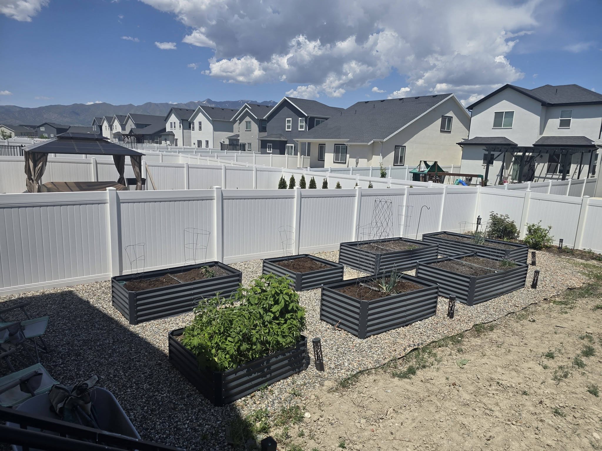 Fenced backyard with a residential view, a garden, and a gazebo