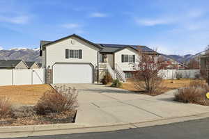 View of front of house with a mountain view, driveway, and a gate