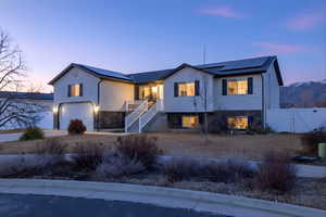 View of front of house with solar panels, a gate, an attached garage, concrete driveway, and stone siding