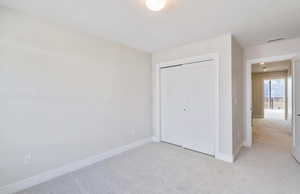 Bedroom 2 with light colored carpet and a closet