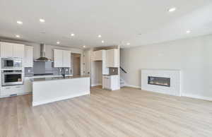 Kitchen with stainless steel appliances, open floor plan, white cabinets, a kitchen island with sink, and recessed lighting