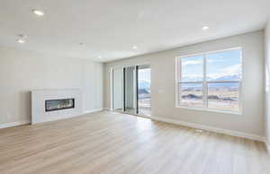 Unfurnished living room with a mountain view, a tile fireplace, light wood-style floors, and recessed lighting