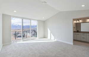 Owner's Suite with a mountain view, floor to ceiling windows, light carpet, recessed lighting, and vaulted ceiling