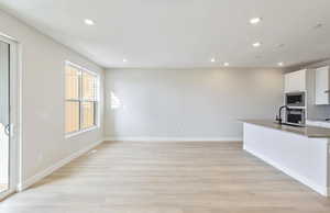 Kitchen with white cabinetry, an island with sink, light wood-style floors, recessed lighting, and stainless steel appliances