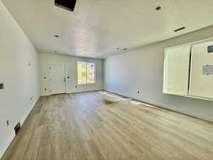 Empty room with a textured ceiling and light wood-type flooring
