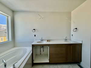 Full bath featuring double vanity, a bath, and a textured ceiling