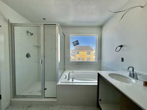 Full bath featuring vanity, a bath, a textured ceiling, and a stall shower