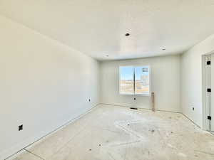 Unfurnished room with baseboards and a textured ceiling