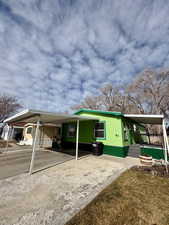 Manufactured / mobile home featuring driveway, a carport, a front yard, and a patio area