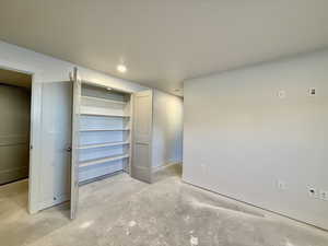 Unfurnished bedroom with concrete flooring, a closet, and recessed lighting