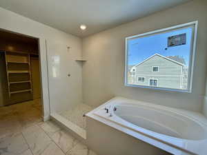 Full bathroom with a garden tub, a spacious closet, a walk in shower, marble look tile flooring, and recessed lighting