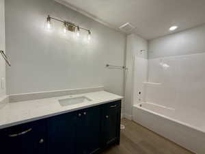 Bathroom featuring vanity, wood finished floors, shower / bath combination, and recessed lighting