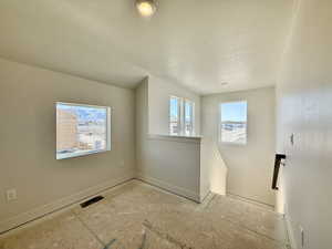 Unfurnished room with baseboards and a textured ceiling