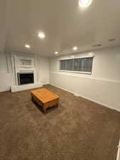 Unfurnished living room with dark carpet, a fireplace, and recessed lighting