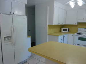 Kitchen featuring white appliances, white cabinetry, light countertops, and light tile patterned floors
