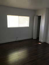 Unfurnished bedroom with dark wood-style flooring and a closet